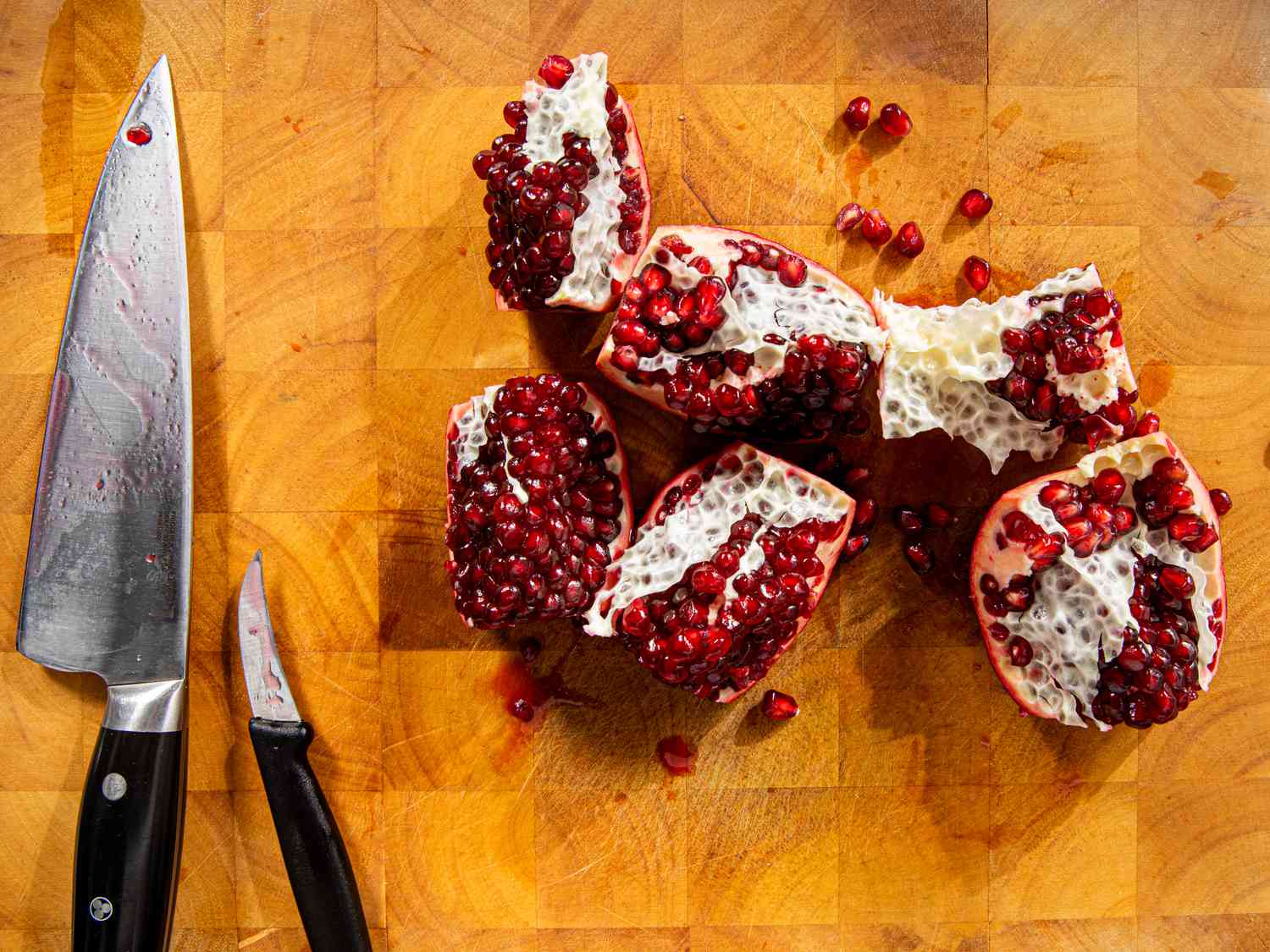 Overhead view of pomegranate in pieces on a cutting board 