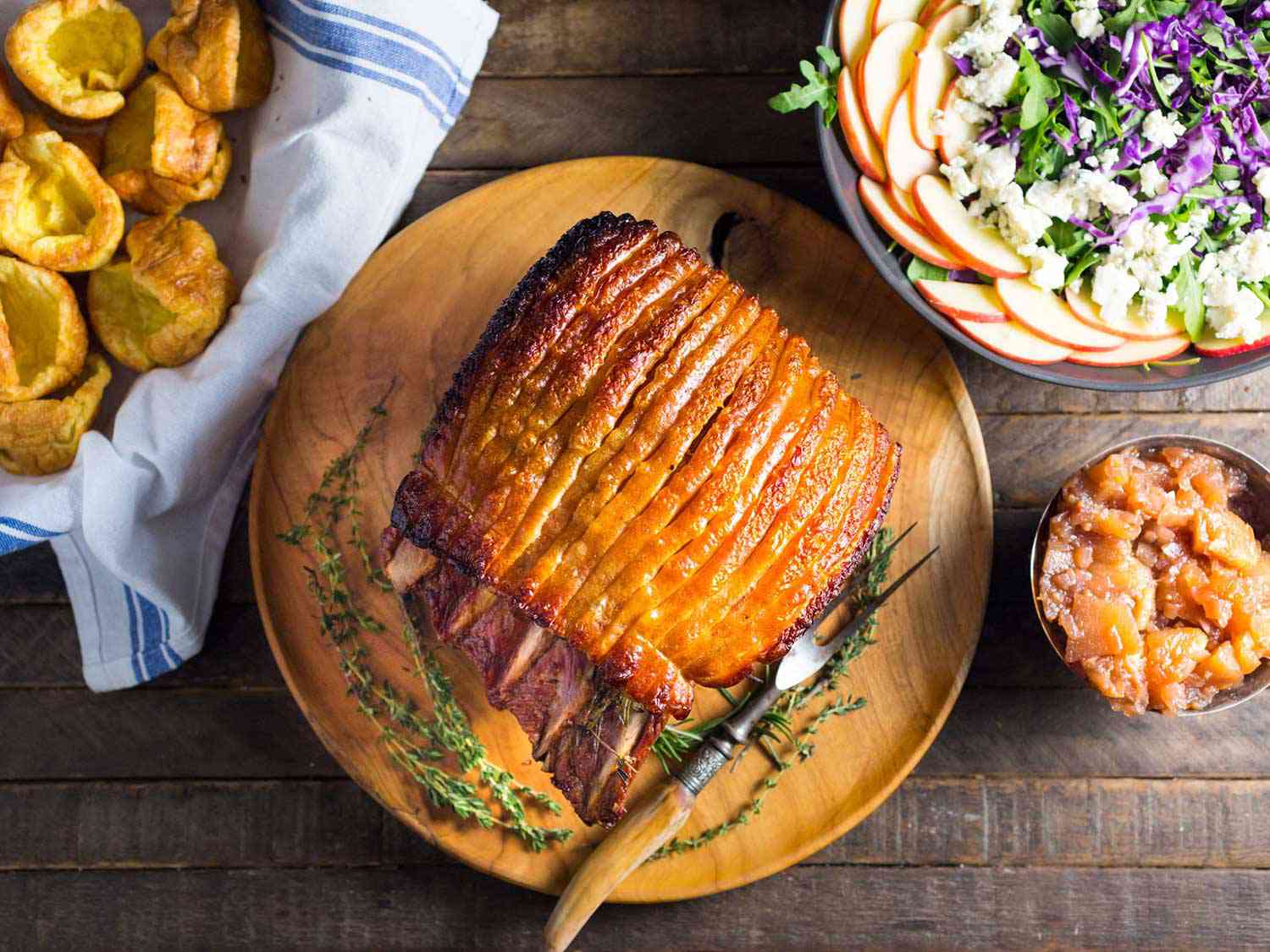 Overhead of a pork loin roast with golden crackling surrounded by sides