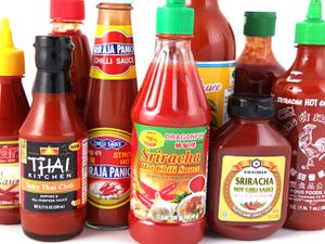 Assorted bottles of different brands of sriracha. 