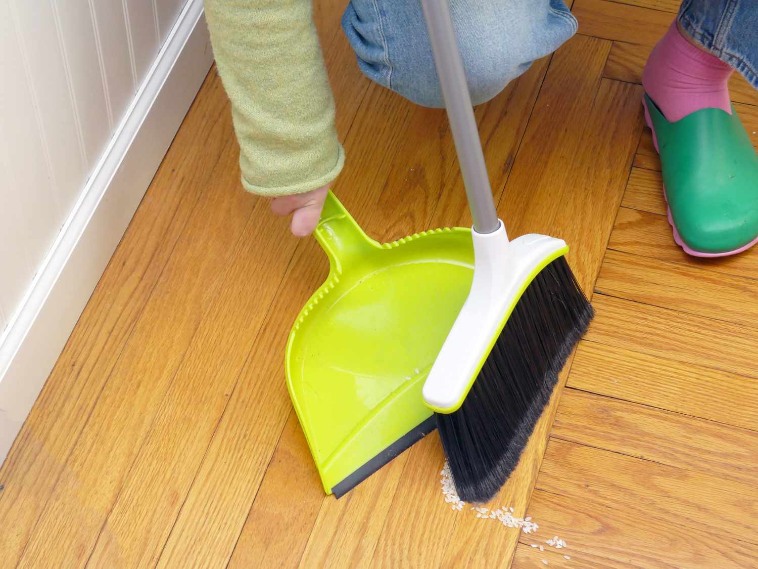 a person sweeping up rice with the casabella dustpan and broom