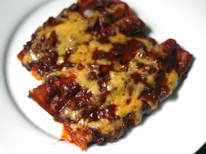 A plate of Tex-Mex cheese enchiladas covered in red chile gravy and a melted cheese 
