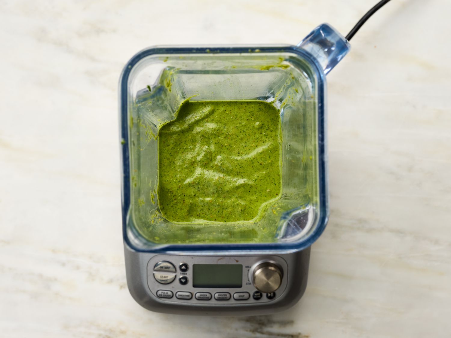 Blender with green sauce viewed from above