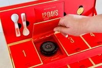A hand opening a door on the Caviar Co 12 Days of Caviar Advent calendar to reveal a jar of salmon roe