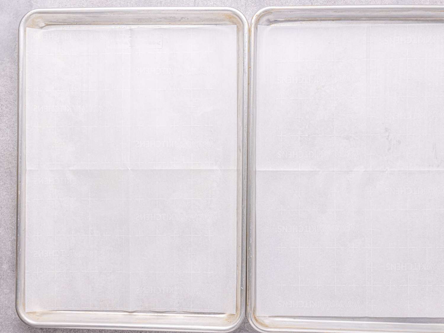 Two empty baking trays lined with parchment paper