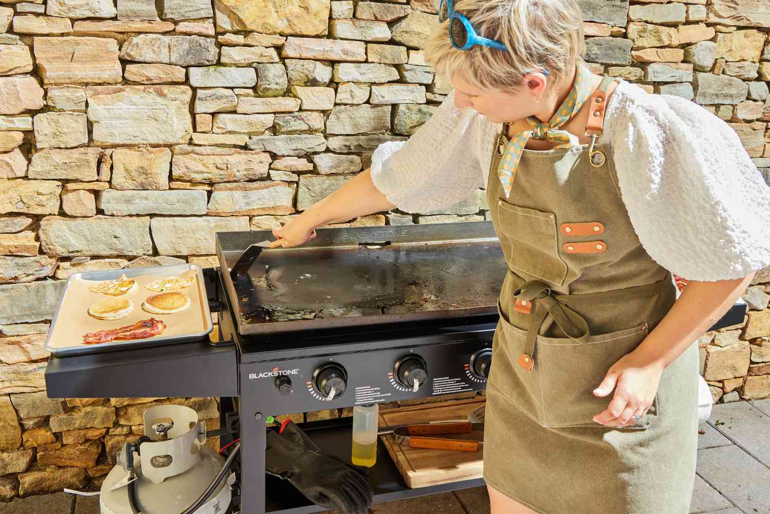 A person cleans the Blackstone 1554 Cooking 4 Burner Flat Top Gas Grill