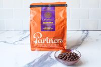 A package of Partners Coffee Bedford espresso with a bowl of coffee beans