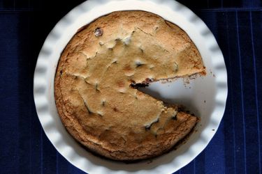 Chocolate chip cookie pie from overhead, with a slice missing.