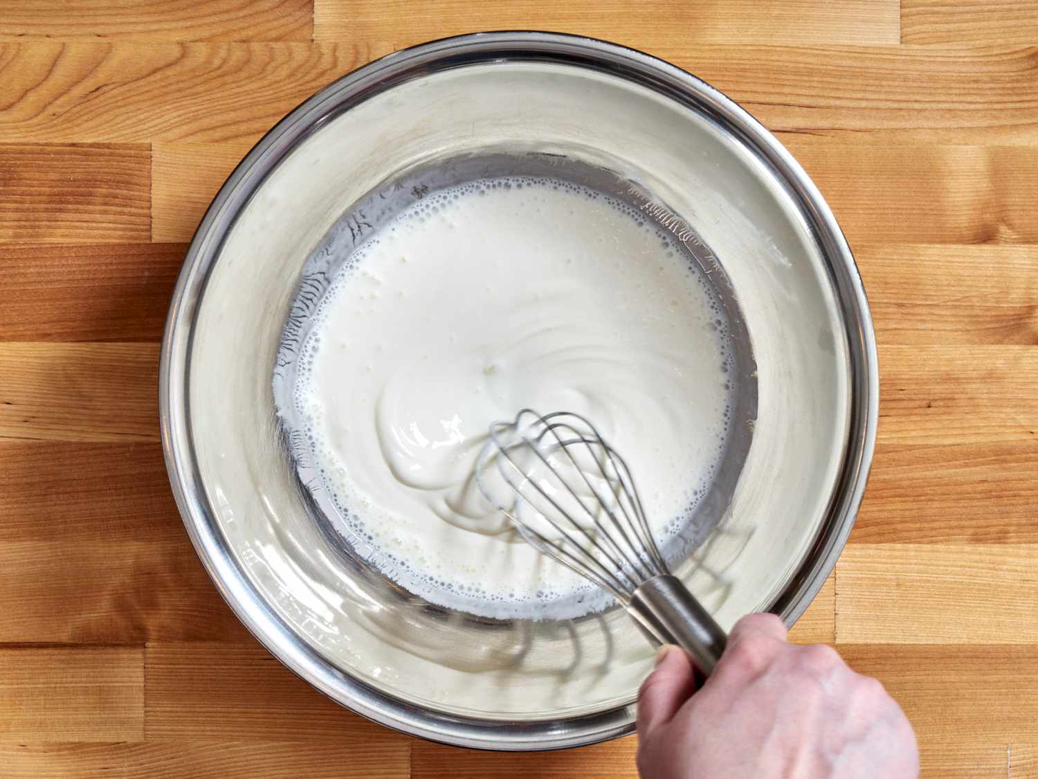 Buttermilk and sour cream being whisked together in a bowl.