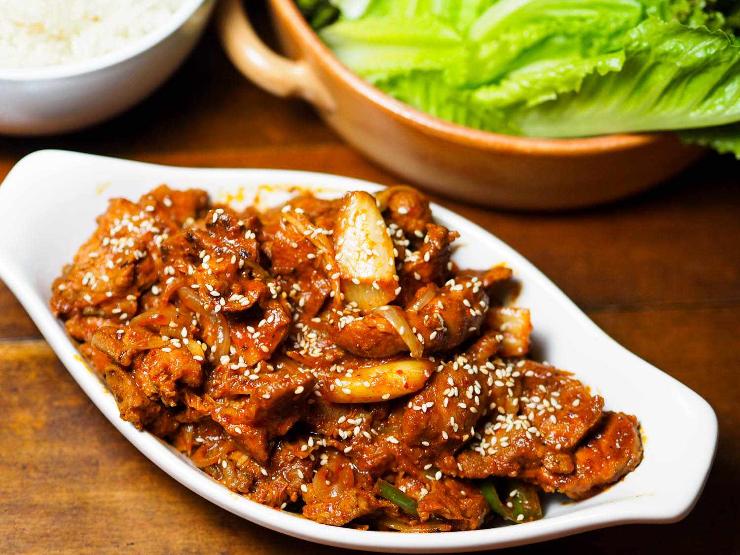 Close-up of jaeyook kimchi bokum, served with rice and lettuce leaves, ready to eat.