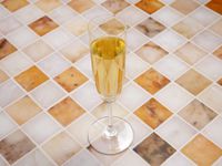 riedel vinum champagne glass with sparkling wine inside on a marble tile surface