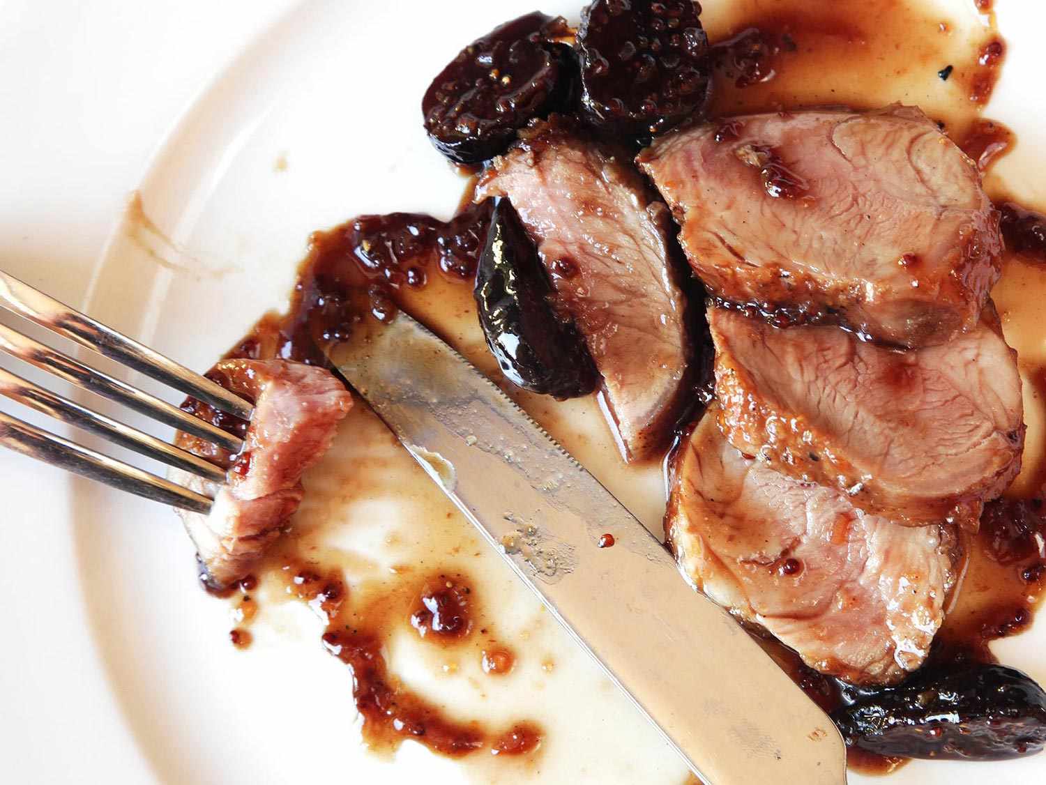 A pork piecing through a slice of pan-roasted pork tenderloin with bourbon-soaked figs.