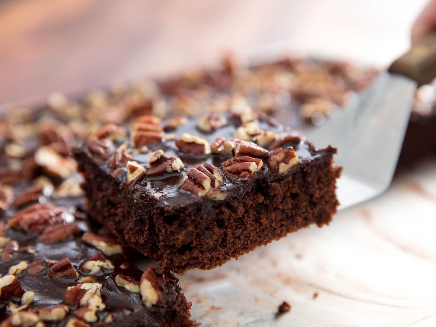 Close-up of a spatula lifting a square of Texas sheet cake.