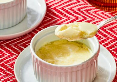 A serving of ginger pudding in a ramekin with a spoonful lifted out placed on a red patterned cloth