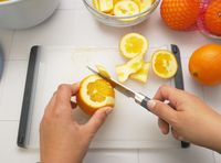 person using cangshan paring knife to supreme an orange