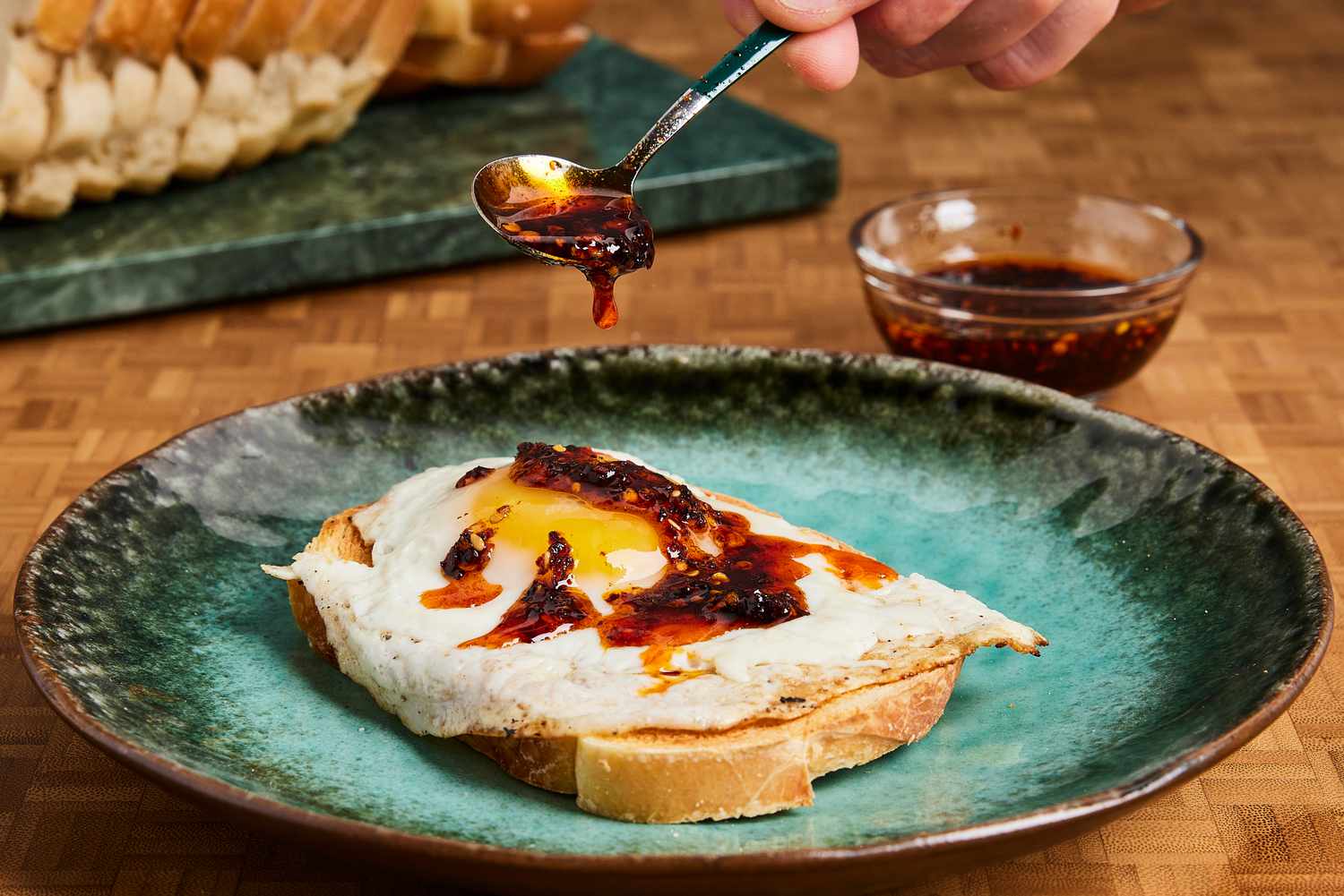 Chili crisp being drizzled onto a fried egg on toast.