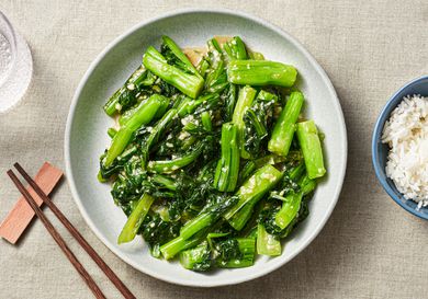 Stir-fried choy sum with minced garlic on a serving platter and a side of Jasmine rice in a small bowl