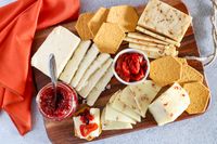 Cheese slices, crackers and condiments from Curdbox Cheese Subscription Box arranged on a wooden board