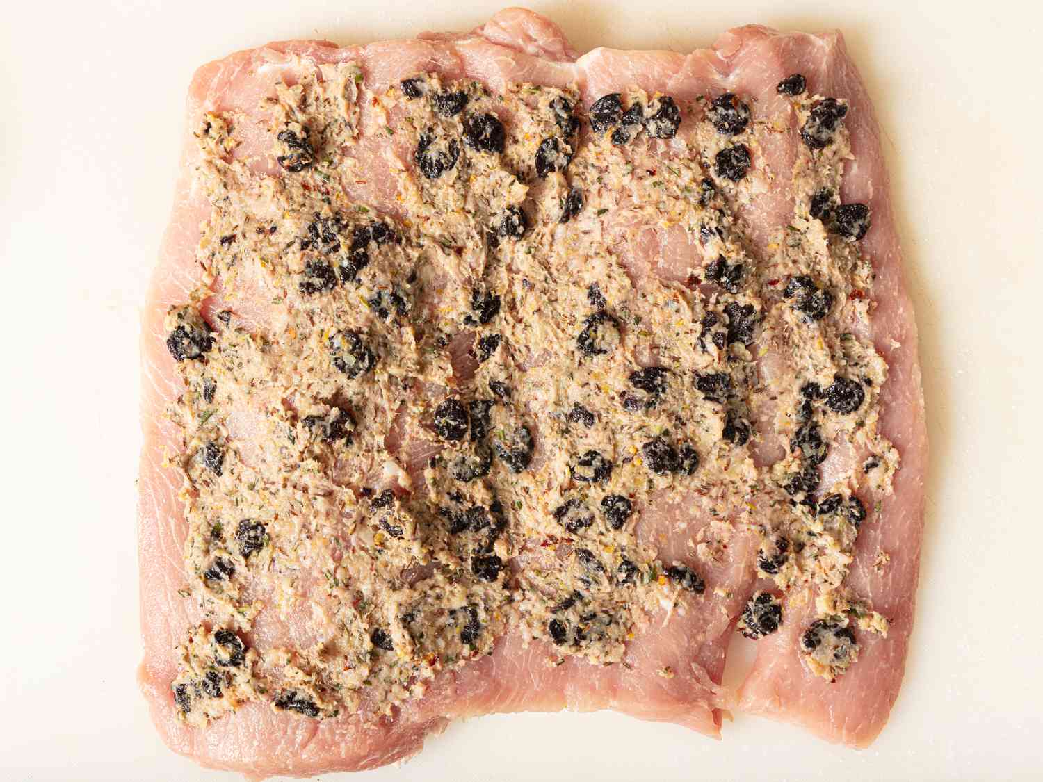 Spreading pancetta paste onto pork loin 