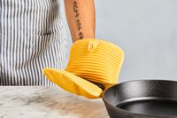 a person using the kitchenaid pot holder to hold the handle on a cast iron skillet