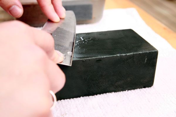 Hands sharpening a knife on a lower grit whetstone