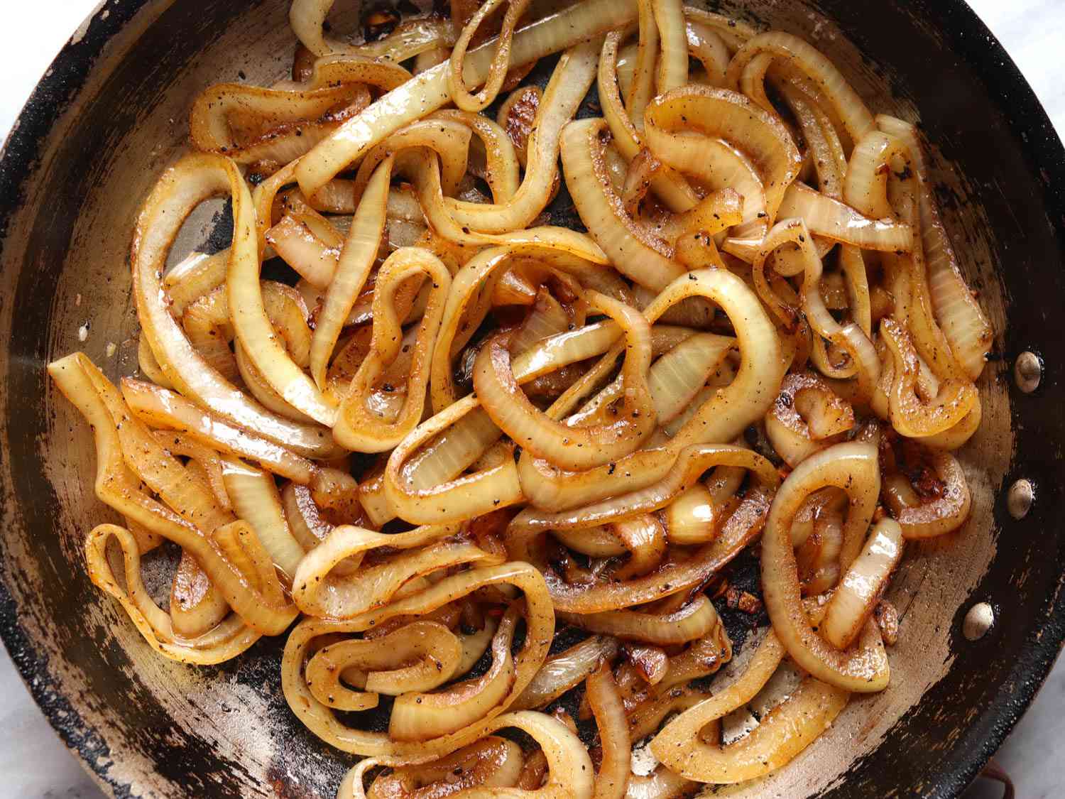 Caramelized sliced onions in a skillet.
