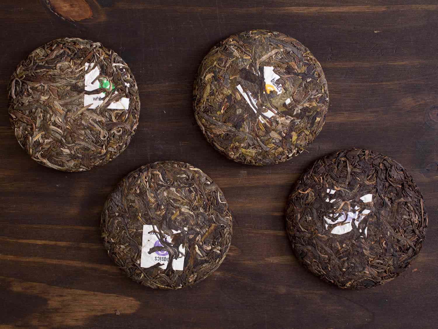 Four pu-erh compressed tea cakes on a wooden surface