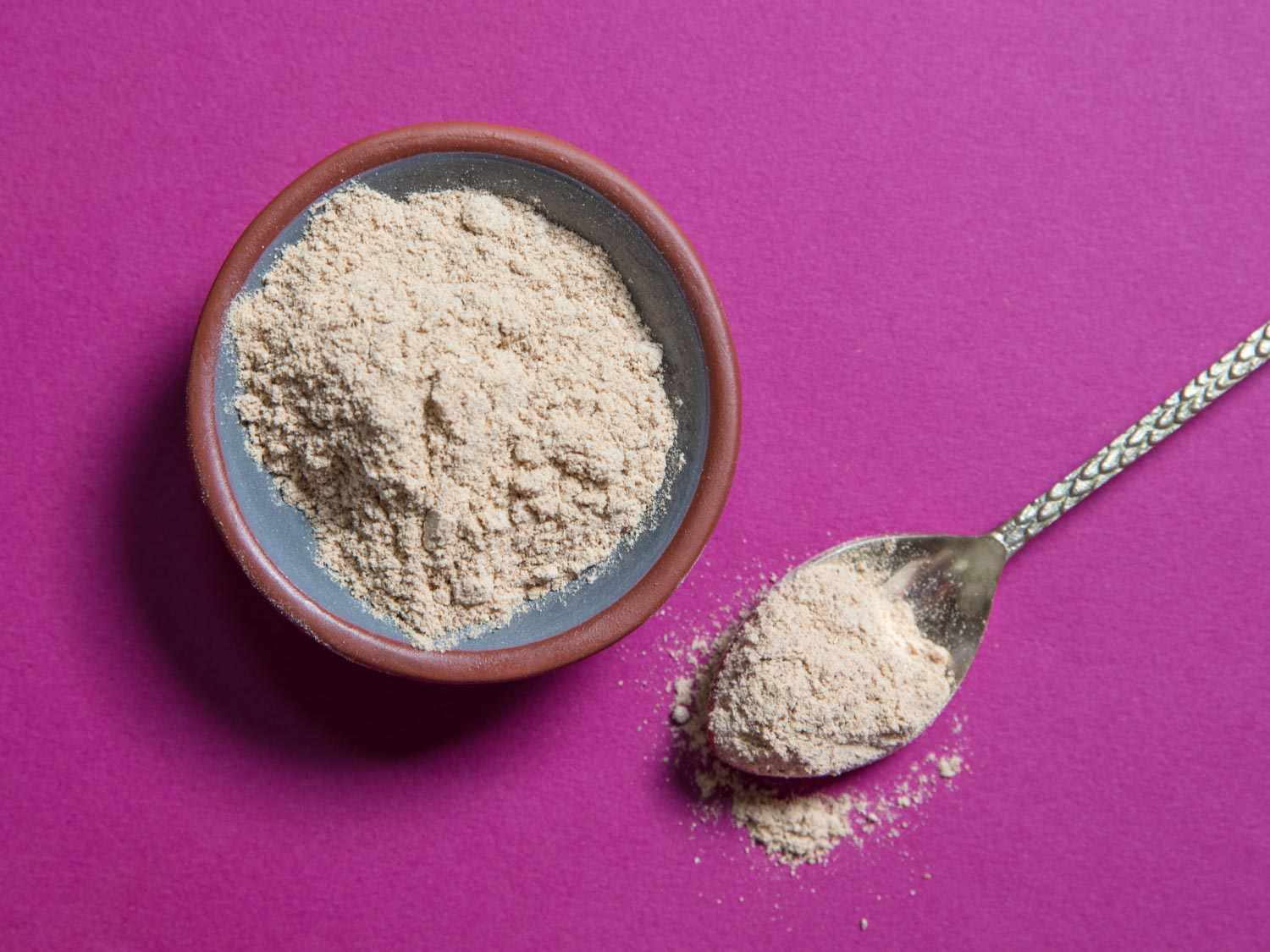 A small bowl and spoon full of amchur powder.