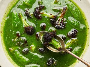 A green soup with broccoli leeks and snap peas served with a spoon