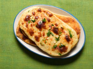 Garlic Naan on a white plate on a lime green tablecloth