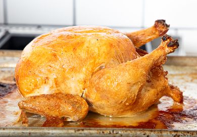 A roasted chicken placed on a baking tray photographed in a kitchen setting