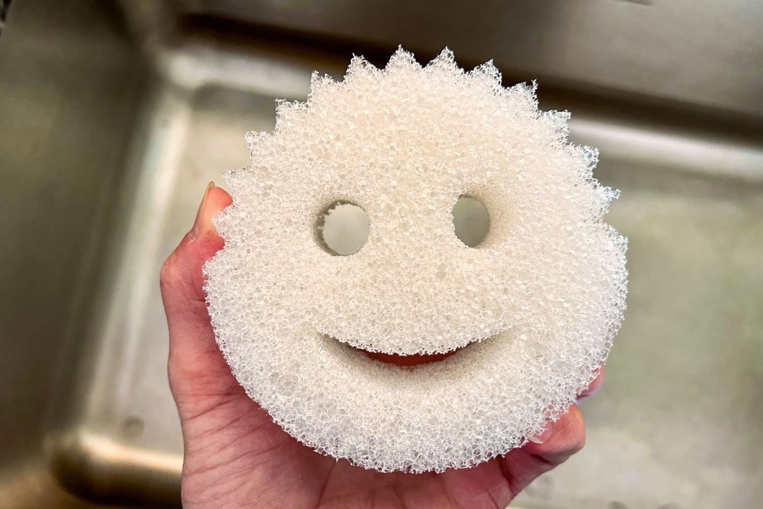 A hand holding the Scrub Daddy sponge
