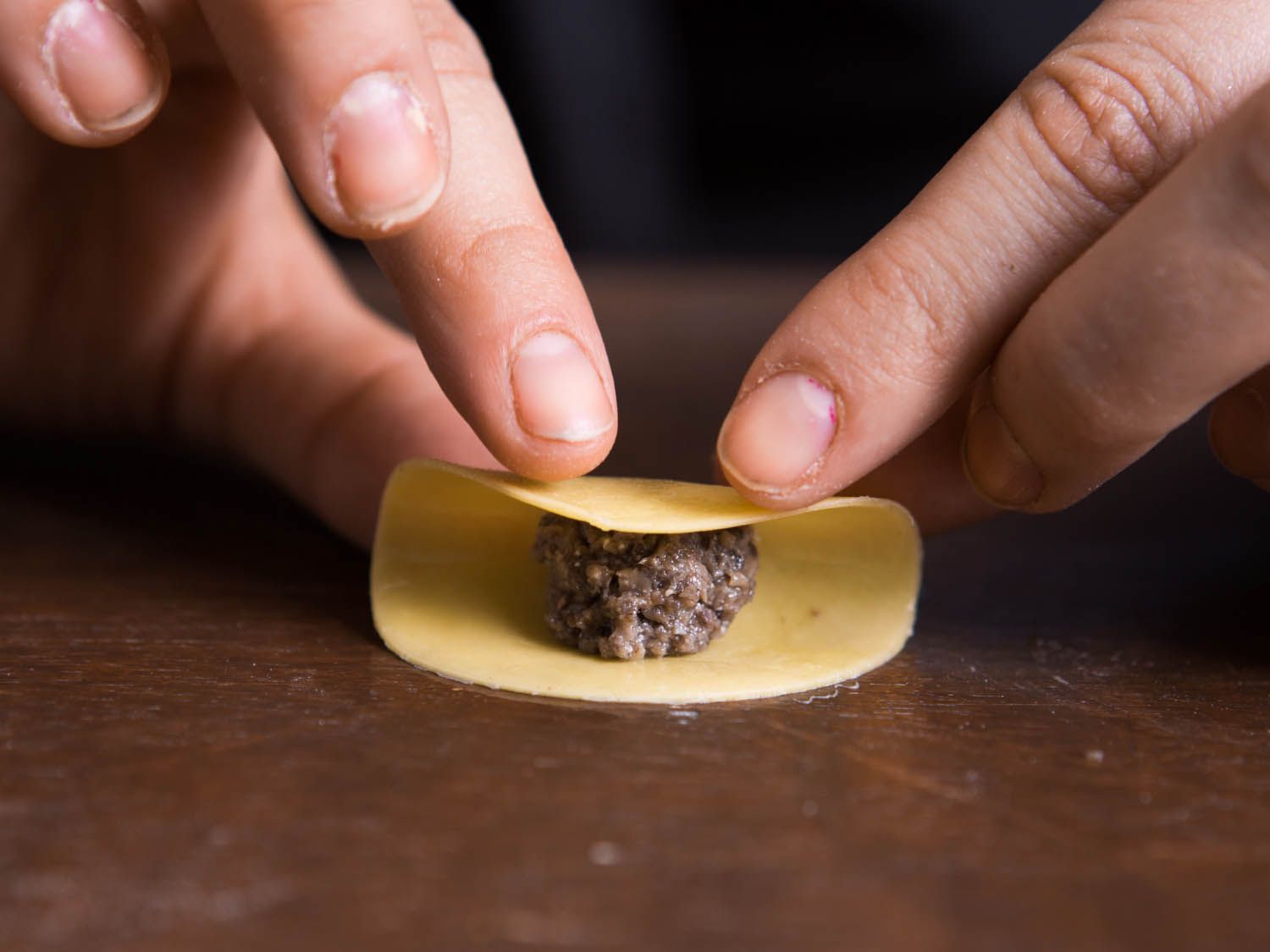 Rolling the dough circle for tortellini into a half moon shape. 
