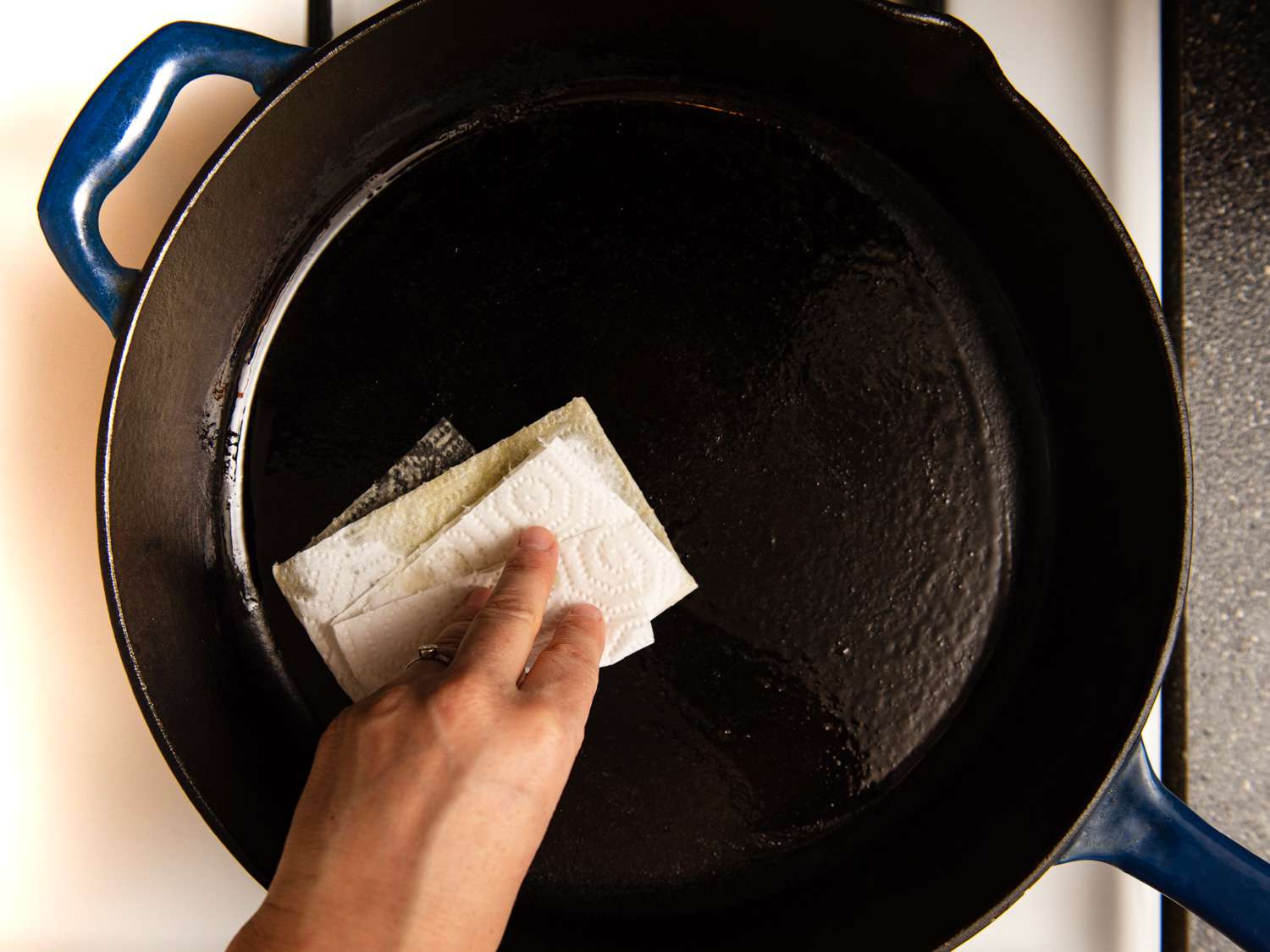 Rubbing a cast iron skillet with an oiled paper towel.