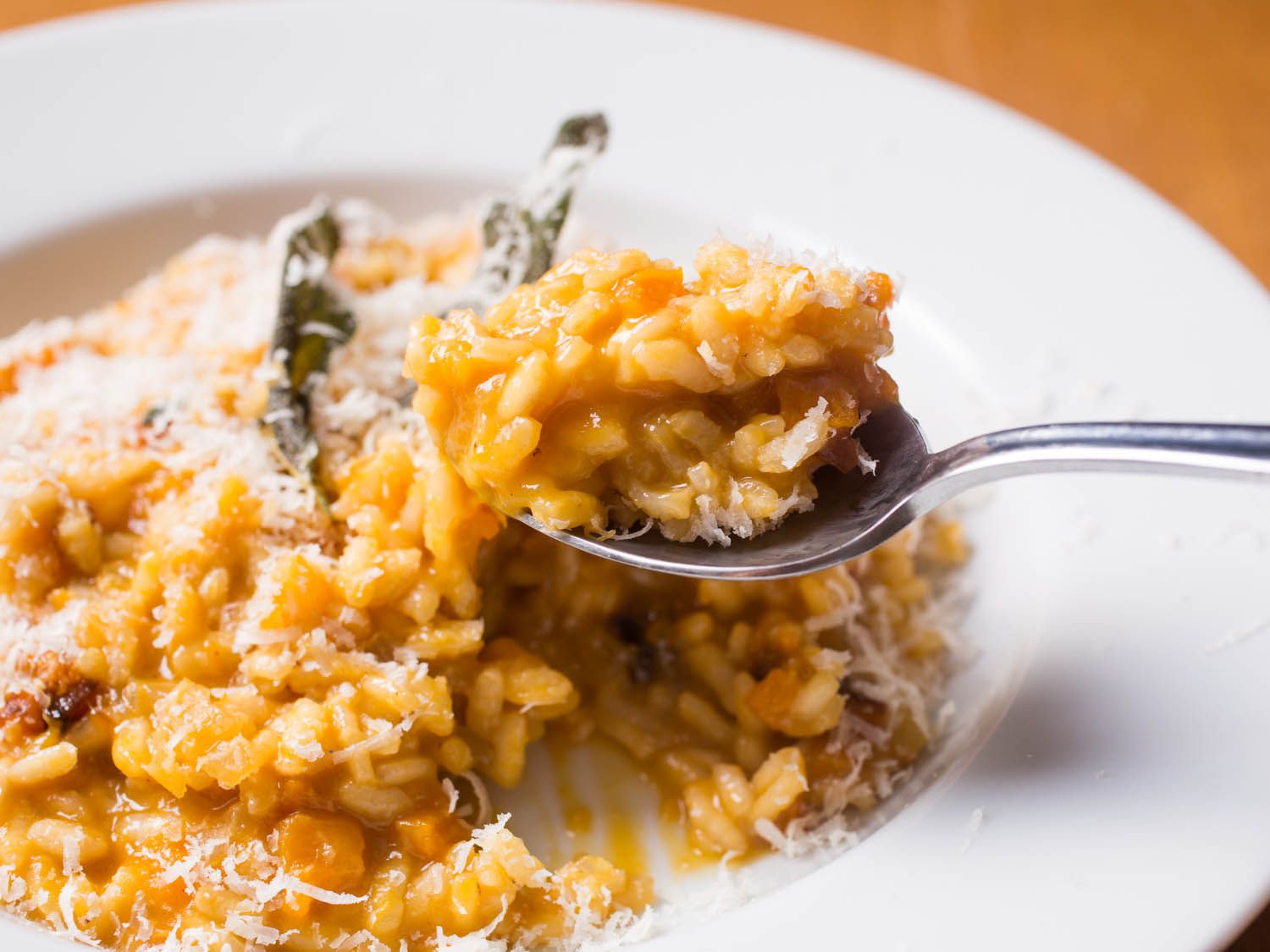 Spooning up butternut squash risotto from a serving plate. 