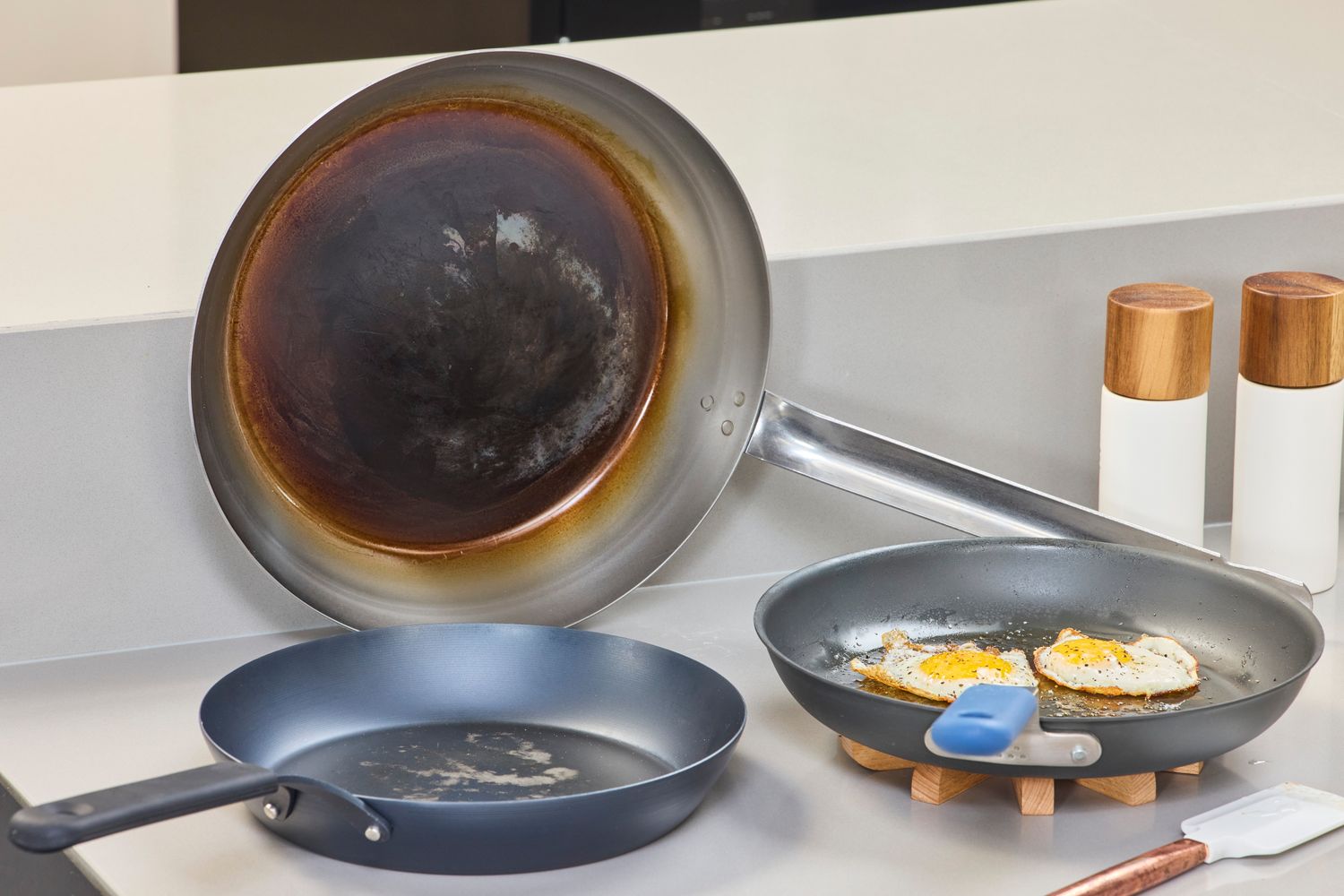 Three carbon steel pans on a kitchen counter