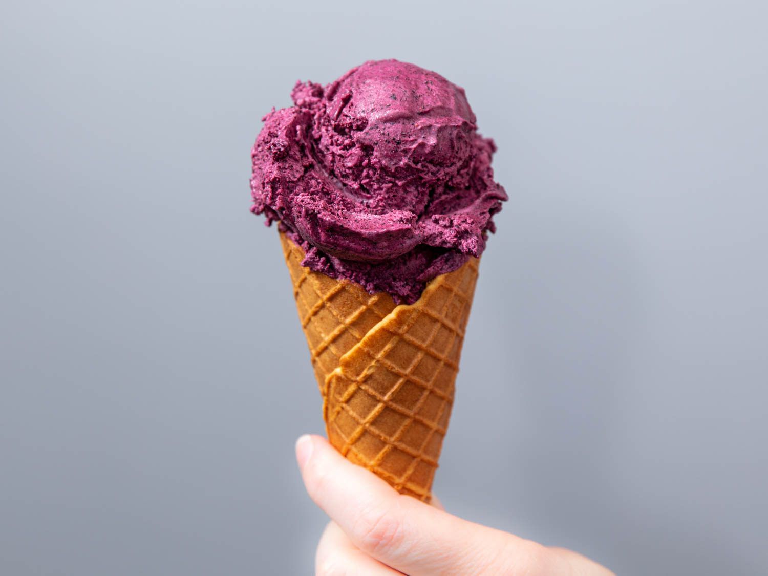 Blueberry ice cream in a cone.