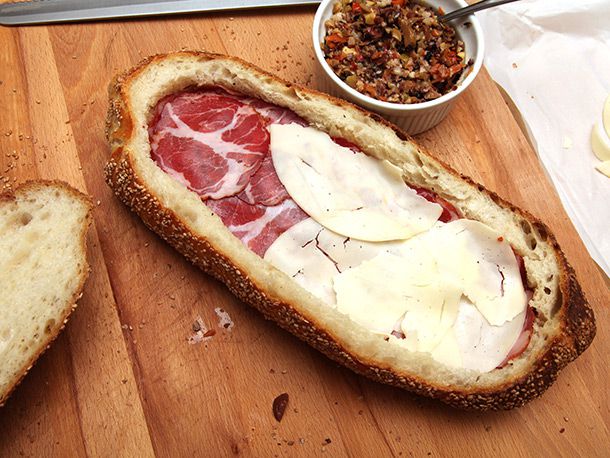 layering sliced provolone over capicola in bread boat