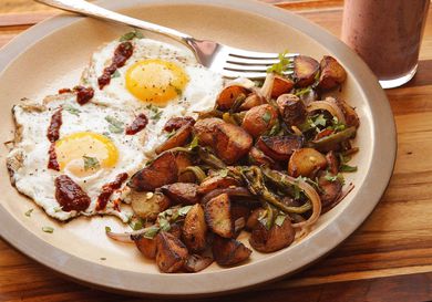 Plate with two sunny side-up eggs, a pile of home fries, and a fork