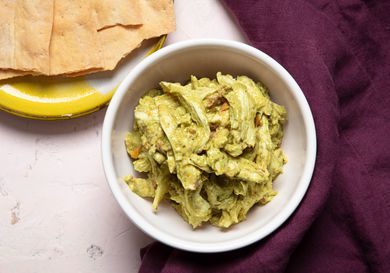 A bowl of pesto chicken salad with crackers on the side