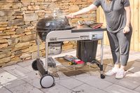 A person standing by the Weber Performer Deluxe Charcoal Grill 22
