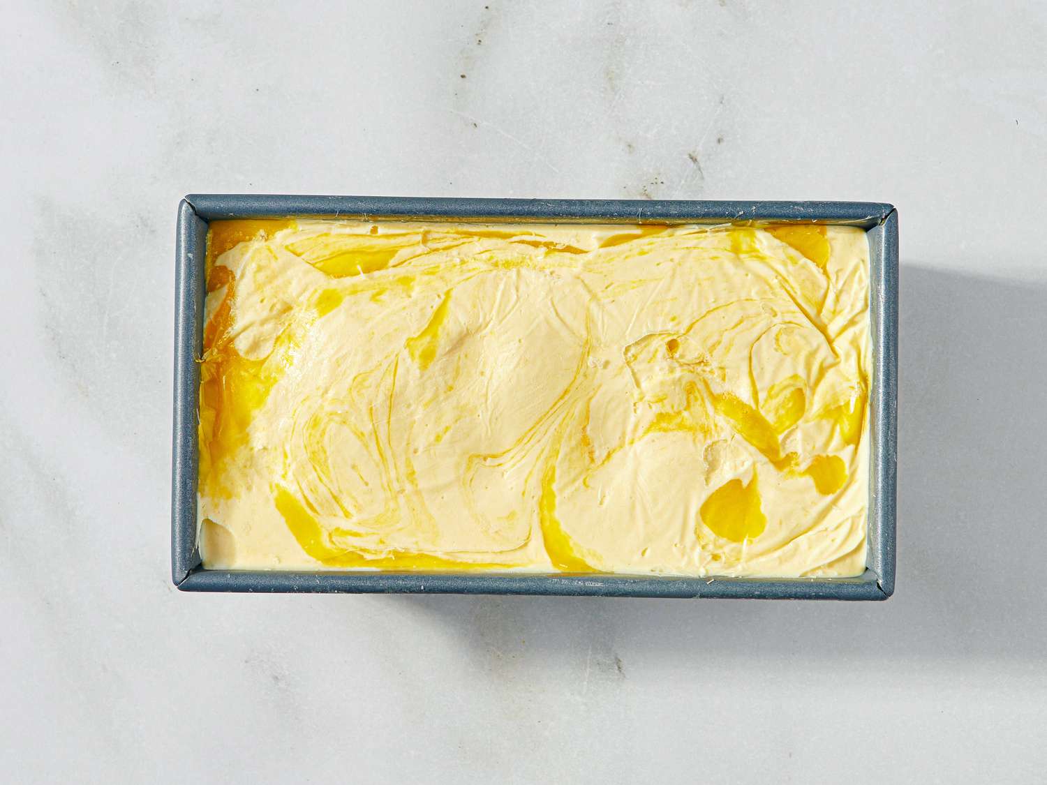 A tray of homemade nochurn mango ice cream with a swirled top