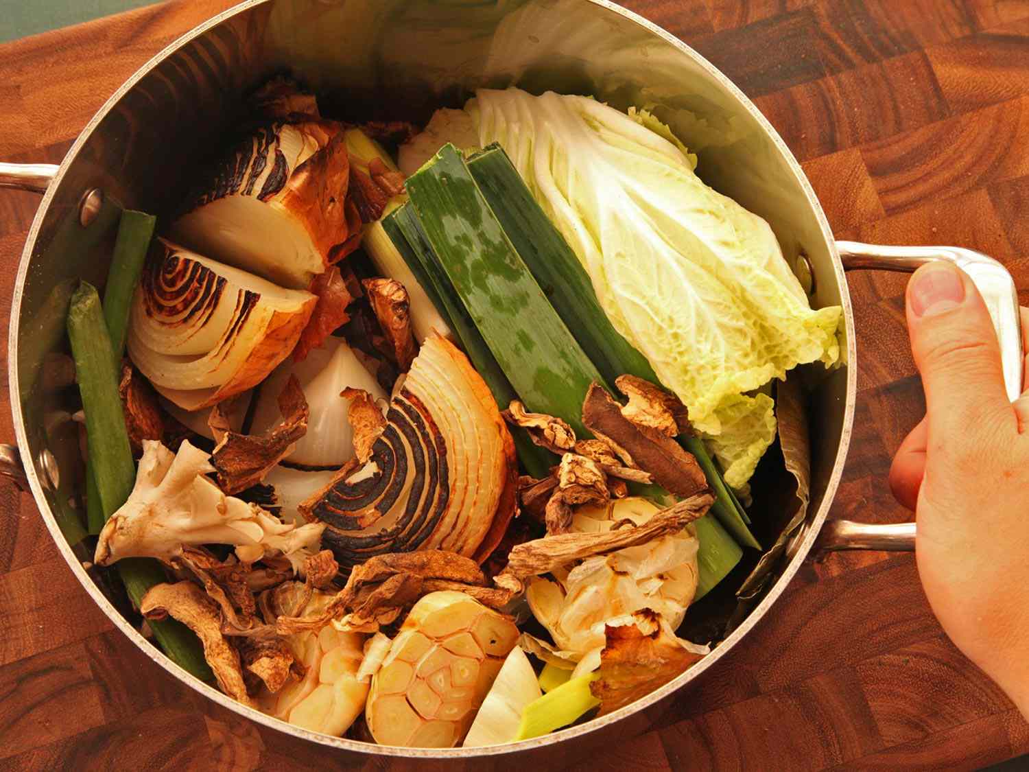 Charred and raw produce in a stock pot before adding water and simmering to make stock for creamy vegan ramen.