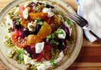 An overhead view of a colorful plate of beet and citrus salad with a pistachio dressing. 