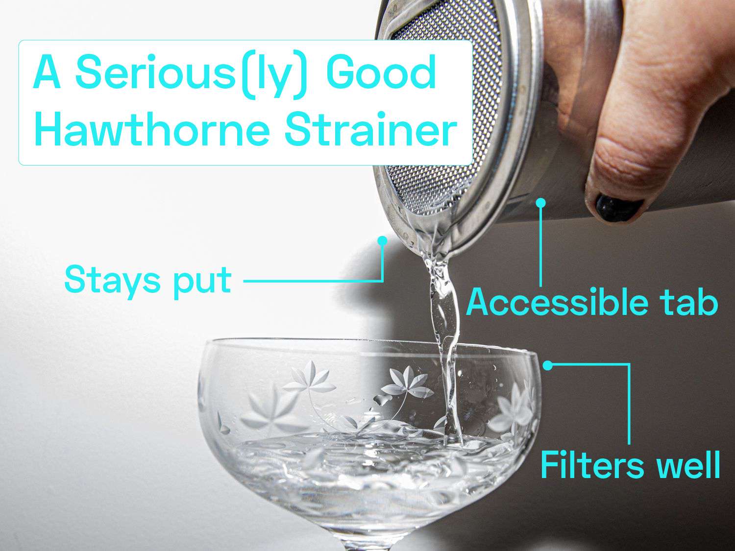 A person straining liquid into a coupe glass from a hawthorne strainer fitted on a mixing tin.