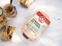 ham in a package on a blue surface with bread and mustard