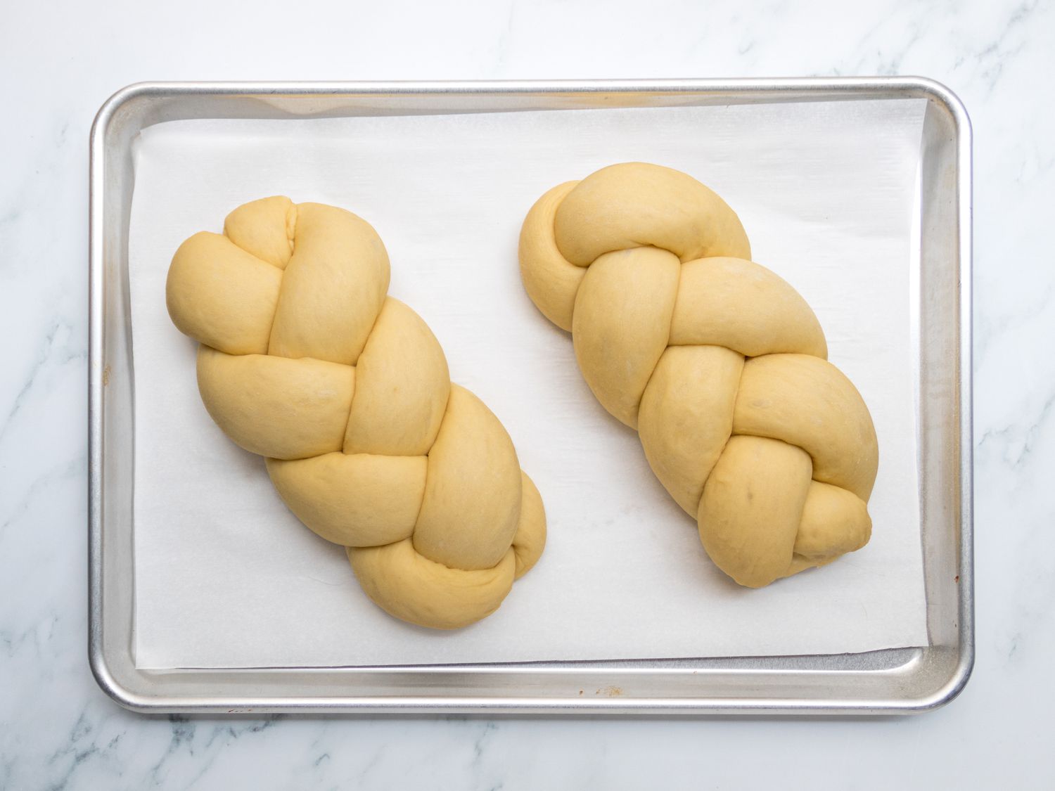 two rad dough loaves on parchment paper on sheet pan