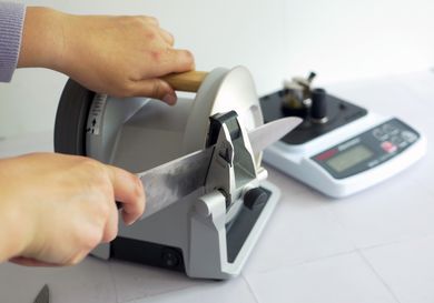 a person using a knife sharpener to sharpen a chef's knife
