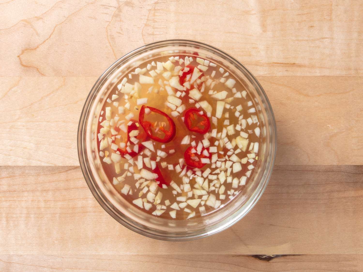 Dipping sauce with sliced red chile in a small glass bowl