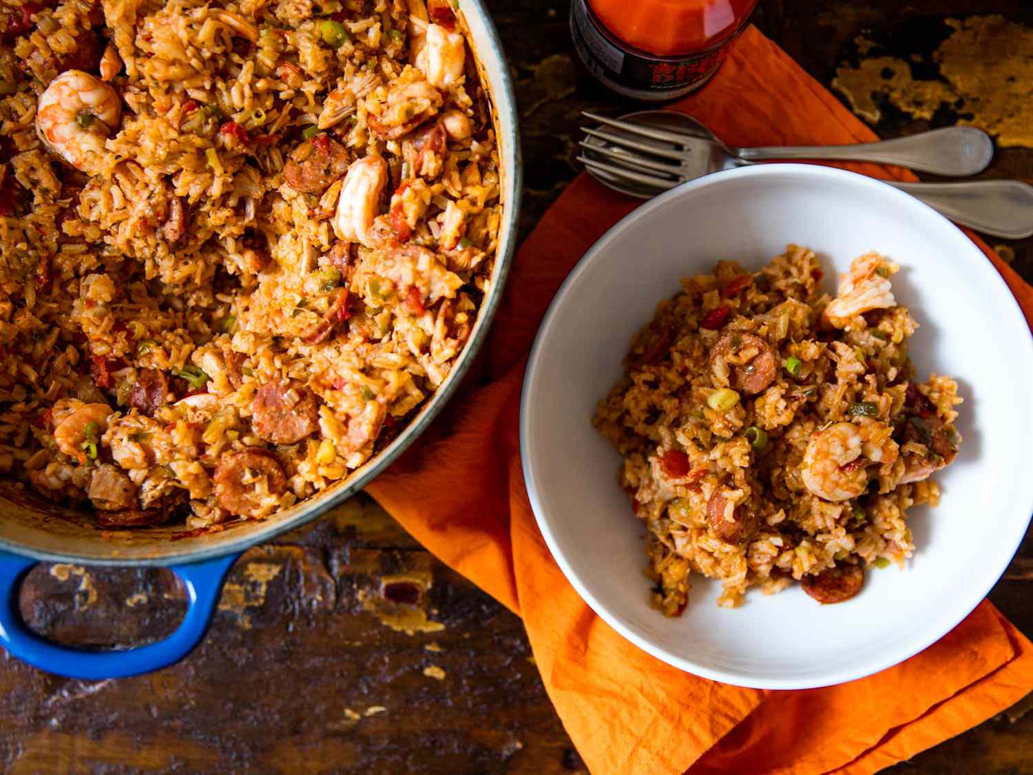 Overhead view of Creole-style red jambalaya being served in a white bowl from a Dutch oven.