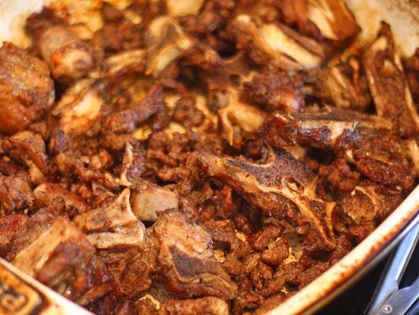 Roasted beef neck bones and stew meat in a baking dish. All of the pieces are well-browned.